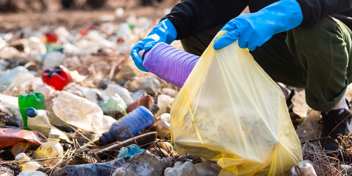 Immagine che raffigura una persona che raccoglie rifiuti in plastica inserendoli in una busta
